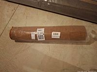 Rolled taupe rug in plastic wrap