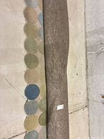 Rolled rug showing multicolor circle border and attached pad