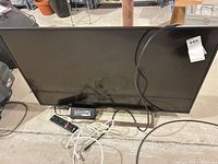 Front view of Sony 43-inch TV with cords, remote and power adapter visible