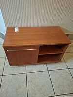 Full view of wood stand showing cabinet door, shelves, handle