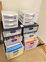 Overall lot: two black drawer carts with two white desktop organizers on top, drawers partially open showing contents