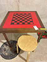 Folding card table with checkerboard top and round Ikea stand positioned on top