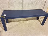 Full view of navy blue rectangular table against concrete wall