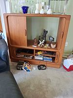 Front view of teak media cabinet showing sliding door compartment and open shelves