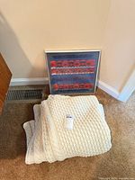 Blanket folded on floor with framed woven textile behind