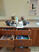 overall vanity view showing blood pressure monitor, cuff, earplugs, first-aid boxes, drawers with soaps and toiletries