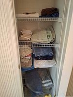 Closet shelves containing folded towels, washcloths and bath rugs