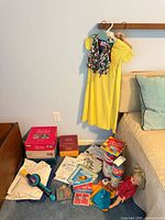 Overview of lot showing dress, vest, board games, toys, books, doll
