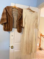 Wedding dress and mink stole hanging on door