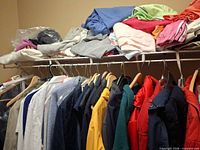 Clothing rack with multiple jackets on hangers and folded garments on shelf