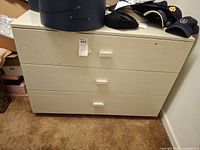 Front view of light beige painted three-drawer chest with rectangular pulls