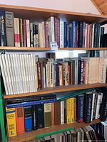 Four shelves densely packed with assorted hardcover and paperback books; titles visible across history, reference and philosophy