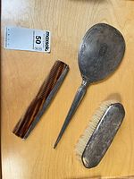 Hand mirror, hairbrush, comb laid out on table