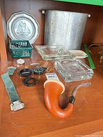 Group shot showing pipe, plate, wastebasket, watch, basket, compass, pins, ashtrays