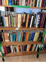 Three wooden shelves filled with approximately 100 assorted books