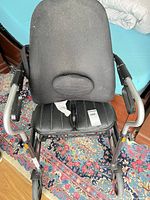Front view showing padded seat, armrests, wheels