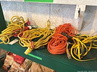 Four coiled items on shelf: yellow rope, yellow cord, orange cord, yellow/black cord