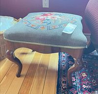 Top view showing needlepoint floral upholstery and wooden legs