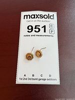 Pair of gold earrings on lot card showing front view and size context