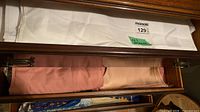 Drawer with white tablecloth and pink linens