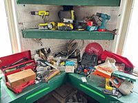 Overview of workbench corner showing hand tools, accessory sets, red toolbox, circular saw blade