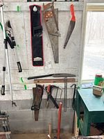 Group view showing loppers, saws on wall, hammers below