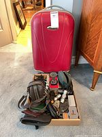 Overall lot showing suitcase behind box of accessories