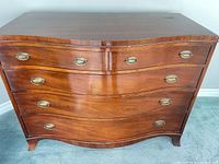 Front view showing bow-front profile, brass pulls, drawer arrangement