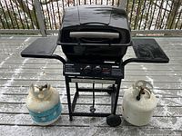 Front view of black Master Chef gas grill with side shelves and two propane tanks