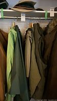 Row of jackets and vests on hanger rail with hats above