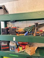 Shelf view showing charger connected, batteries, jack stand, umbrella, and assorted tools