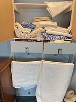 cabinet with multiple folded and hanging white and blue linens