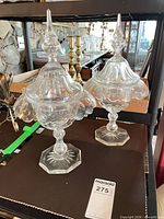 Two clear glass lidded compotes on shelf