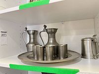 Full view of lot on shelf showing tray with six cups, two lidded jugs, lidded mug