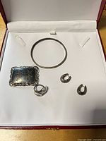 All jewellery pieces laid in box: brooch, ring, bangle, pair of earrings