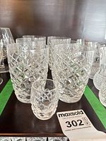 Group of Waterford cut-crystal water tumblers and shot glass on shelf