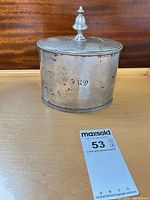 Front view of sterling silver container with lid and finial