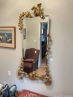 Full view of rectangular ornate gold wall mirror hanging on wall