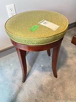 Full view of stool showing wood frame, legs and green cushion