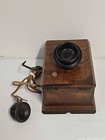 Front view of wooden telephone showing Bakelite mouthpiece and receiver cord