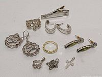 All 12 sterling silver pieces laid out: tie clip, rings, earrings, pendants