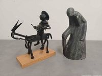Both sculptures side by side on surface: metal Don Quixote on left, soapstone figure on right
