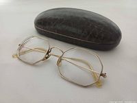 Eyeglasses next to closed brown textured case