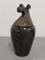 Front view of black canopic jar showing jackal head lid and hieroglyphics