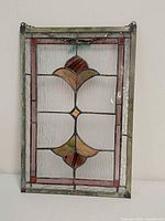 Full frontal view of stained glass panel showing design, frame, chain