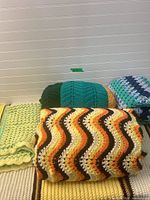 Four folded afghans showing overall colors and patterns