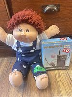 Cabbage Patch Kid doll beside Whisper 2000 boxed set