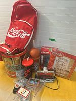 Group shot of Coca-Cola tin, canvas bag, tumblers, Yahtzee game, clock radio, trading cards