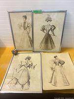 Group shot of three framed prints and one unframed print on table, Rubik's cube for scale