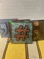 Three metal panels with punctuation symbols displayed together